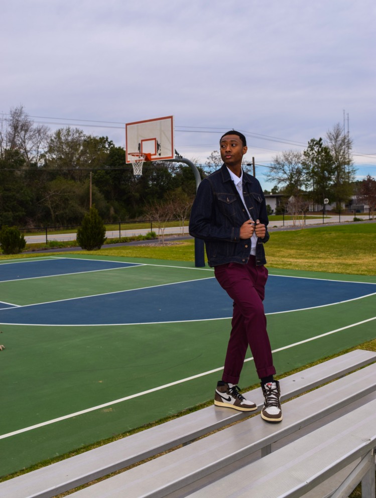 Man stands on bleachers beside outdoor basketball court